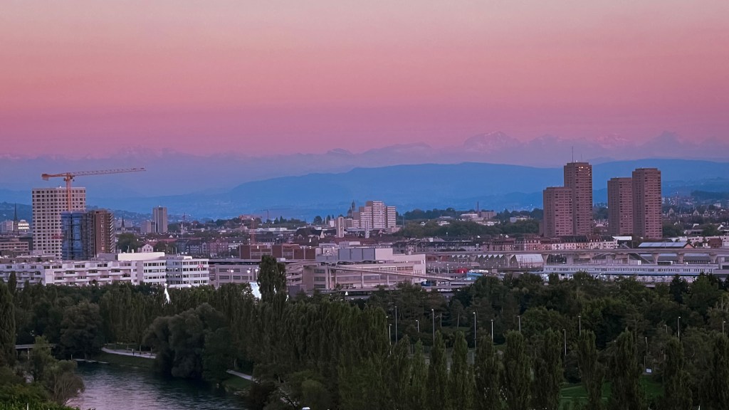 A scenic view of the city of Zurich from Alstetten vineyard during sunset with a cotton candy hue sky in the horizon